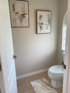 a bathroom with a toilet and two pictures on the wall at The Elegant Suite in Shared House in Cape Coral