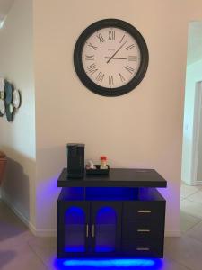 a clock on the wall above a table with blue lights at The Elegant Suite in Shared House in Cape Coral