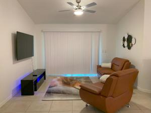 a living room with two chairs and a flat screen tv at The Elegant Suite in Shared House in Cape Coral
