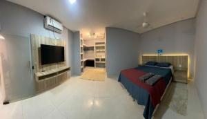 a bedroom with a bed and a flat screen tv at Casa 108 in Guaibim