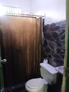 bagno con servizi igienici e parete in pietra di Koniminto Hostal a Pijao Altre 2 foto