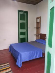 una camera con un letto blu e una porta verde di Koniminto Hostal a Pijao