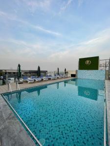 a large swimming pool with lounge chairs on a roof at Luxury condo with rooftop pool! in Islamabad