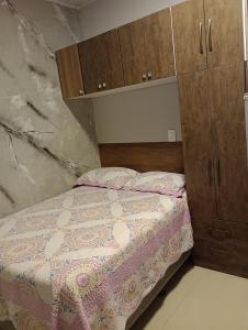 a small bedroom with a bed and wooden cabinets at kitnet 2 in Balneário Camboriú