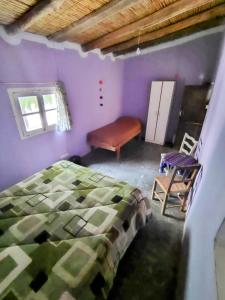 a bedroom with purple walls and a bed and a chair at Casa Colores in Tilcara +20 photos