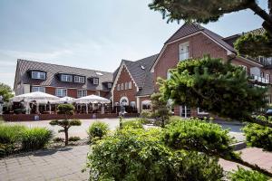 a large brick building with trees in front of it at Hotel Neuwarft in Dagebüll