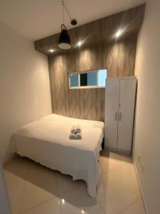 a bedroom with a white bed and a cabinet at Casa Itapema/SC pertinho do mar! in Itapema