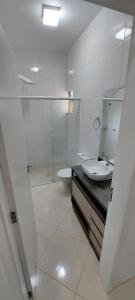 a white bathroom with a sink and a toilet at Casa Itapema/SC pertinho do mar! in Itapema