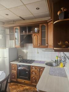 a kitchen with wooden cabinets and a stove and a sink at 2 комнатные аппартаменты на бульваре Пушкина in Kremenchuk