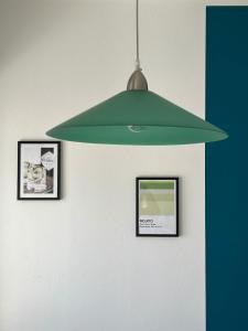 a green pendant light hanging from a wall with two pictures at Nandi-HolidaySport&Relax-Apt in Tarvisio