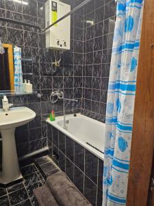 a black tiled bathroom with a tub and a sink at 2 комнатные аппартаменты на бульваре Пушкина in Kremenchuk +6 photos