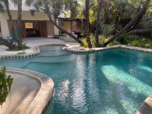 a swimming pool with palm trees in a courtyard at Sandy Feet Retreat in Malindi