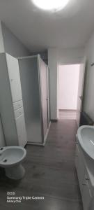 a white bathroom with a toilet and a sink at Apartamento Turístico Cervantes 18 in Losar de la Vera +13 photos