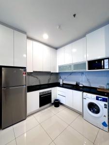a kitchen with white cabinets and a washer and dryer at Societe by Bamboo Hospitality in Kuala Lumpur