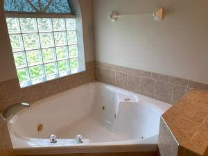 a large white tub in a bathroom with a window at The Elegant Suite in Shared House in Cape Coral