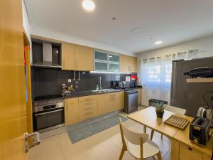a kitchen with wooden cabinets and a table with chairs at Vibing & Liming Ericeira in Ericeira