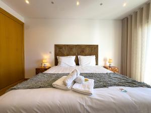 a bedroom with a large white bed with towels on it at Vibing & Liming Ericeira in Ericeira