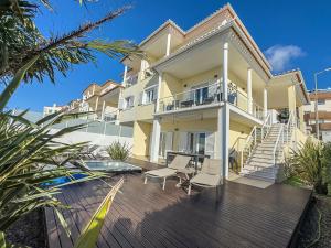 a large yellow house with a deck with chairs at Vibing & Liming Ericeira in Ericeira