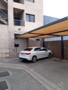 ein weißes Auto parkt auf einem Parkplatz neben einem Gebäude in der Unterkunft Dos Nogales 26 in Villa Carlos Paz