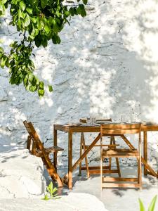 uma mesa de madeira e cadeiras sentadas ao lado de uma parede em A Casa de Canosiña by ALÔGA em Fisterra