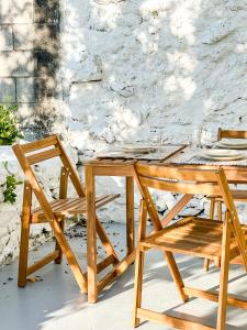 uma mesa de madeira e cadeiras ao lado de uma parede de pedra em A Casa de Canosiña by ALÔGA em Fisterra