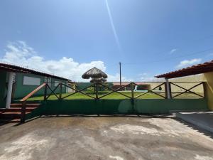 ein Gebäude mit einem grünen Zaun und einem Regenschirm in der Unterkunft Casa de praia in São José de Ribamar