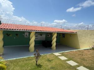 ein grün-gelbes Haus mit einer Terrasse in der Unterkunft Casa de praia in São José de Ribamar