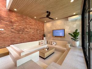 a living room with a couch and a tv on a brick wall at The Damari Villa Umalas in Canggu +29 photos