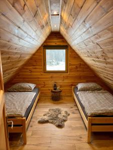two beds in a log cabin with a window at Domki na granicy in Jeżowski Dział