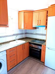 a kitchen with wooden cabinets and a white refrigerator at El Cabanyal 400m from the Beach in Valencia