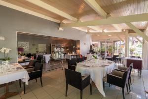 a dining room with white tables and chairs and windows at Logis Hotel - Restaurant Le Relais de Comodoliac in Saint-Junien