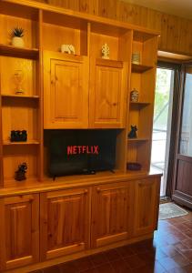 einen TV in einem hölzernen Entertainment-Center in einem Wohnzimmer in der Unterkunft La Casa di Mosk in Castel di Sangro