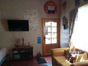 Una sala de estar con un sofá y un televisor. en Departamento Refugio Compinches, Castro Chiloé, en Tentén