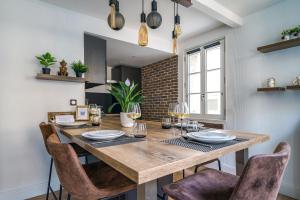 a dining room with a wooden table and chairs at Le Baleschoux - PrestiPlace Collection in Tours