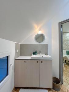 a white bathroom with a sink and a mirror at Le cerisier in Beaumont-en-Véron