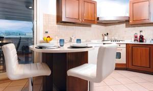a kitchen with a table and white chairs in it at The Roof - Appartamento con terrazza al centro di Civitavecchia in Civitavecchia