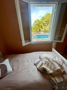 a bed with a window with a view of a pool at La FINCAD4 entre plages et Forêt in Son Parc
