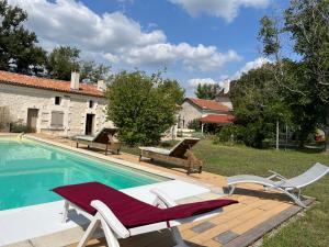 a swimming pool with two lounge chairs next to a house at Maison Périgord vert piscine et spa in La Roche-Chalais