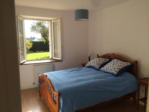 Schlafzimmer mit einem Bett mit blauer Bettwäsche und einem Fenster in der Unterkunft Farmhouse in an amazing private park in Vannes