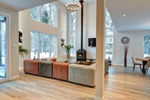 a living room with a large couch and windows at Modern Luxury 4-Bedroom Home by Mont-Tremblant Ski Resort in Lac-Superieur