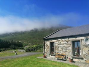 BellanasallyCheerful 3 bedroom cottage with open fire的山前带长凳的石头建筑