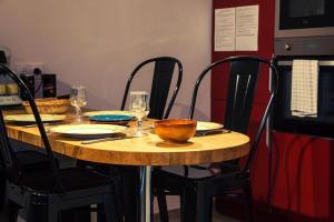 a wooden table with chairs and a bowl on it at Le Clos de Tanvol - Parking privé GRATUIT- Terrasse Privée - Climatisation - Caravane Airstream in Viriat +121 photos