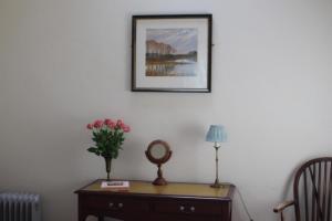 a vase of flowers on a table with a picture on the wall at The Pump House in Athy