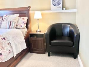 1 dormitorio con silla negra junto a la cama en Cozy Walkout suite with King bed, Kitchen, Parking & Patio, en Calgary