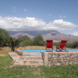 two chairs and a swimming pool with mountains in the background at El Cortijo Tinogasta in Tinogasta