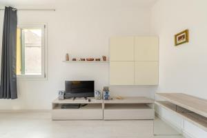 ein weißes Wohnzimmer mit einem TV und einem Schreibtisch in der Unterkunft Charme Padovano con Terrazza in Padua