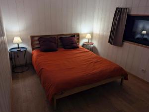 a bedroom with a large orange bed with two lamps at Au Chalet Bourguignon 5 in Salives