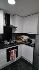 a kitchen with white cabinets and a stove top oven at A Place to Pause, A Place to Belong, Charming Three Bedroom Rainham Retreat with Parking and WiFi in Swindon