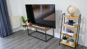 a tv on a stand with a table with a tv at A Place to Pause, A Place to Belong, Charming Three Bedroom Rainham Retreat with Parking and WiFi in Swindon +14 photos