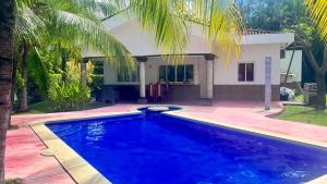 a swimming pool in front of a house at Golden Sunset House in Acajutla